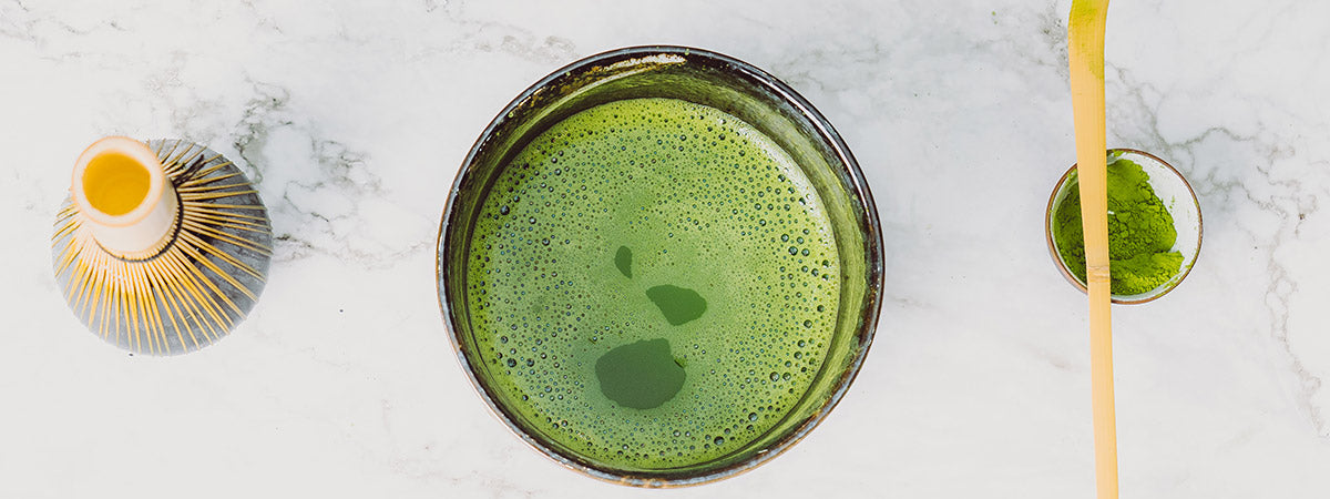 Matcha tea in bowl with bamboo whisk and spatula